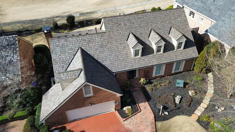 Aerial view of a brick home with dormers during a synthetic shake roof replacement
