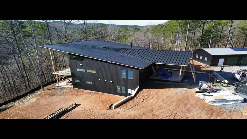 New construction home with a black standing seam metal roof on a wooded North Georgia mountain lot