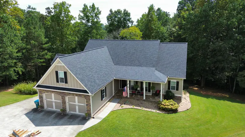 Aerial view of a ranch home with a new gray architectural shingle roof after storm damage restoration
